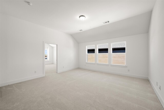 unfurnished room with light colored carpet and vaulted ceiling