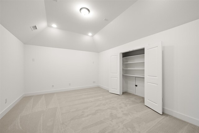 unfurnished bedroom featuring lofted ceiling, a closet, and light colored carpet