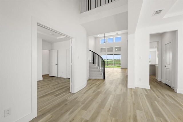 unfurnished living room featuring light hardwood / wood-style flooring and a high ceiling