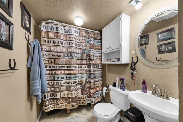 bathroom with tile flooring, sink, toilet, and a textured ceiling