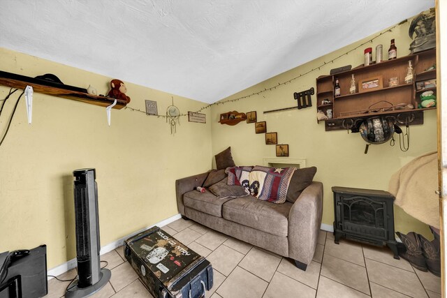 living room with tile flooring, vaulted ceiling, and a wood stove