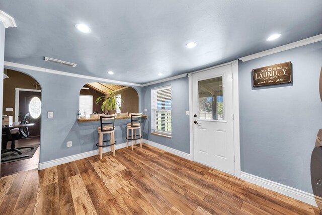 entryway with wood-type flooring and crown molding