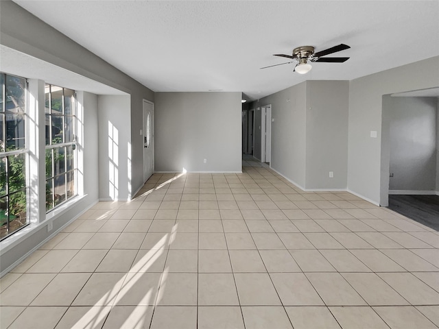 tiled empty room featuring plenty of natural light and ceiling fan