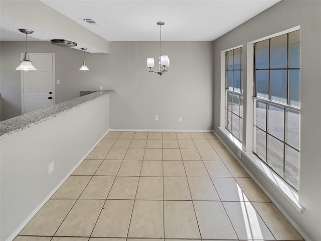 unfurnished dining area with a chandelier, plenty of natural light, and light tile patterned flooring