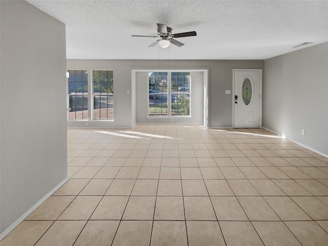 interior space with ceiling fan, a healthy amount of sunlight, a textured ceiling, and light tile patterned flooring