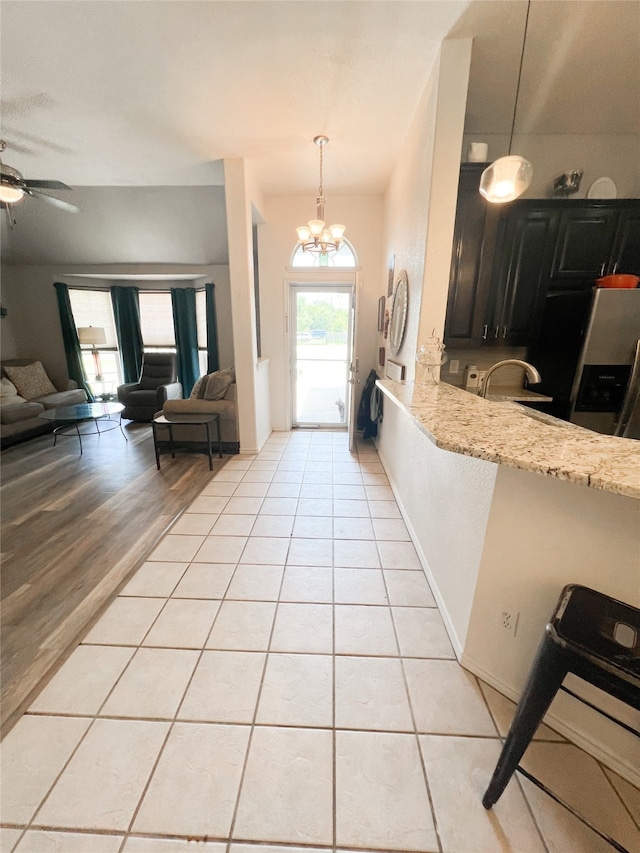 foyer with light wood-type flooring and ceiling fan with notable chandelier