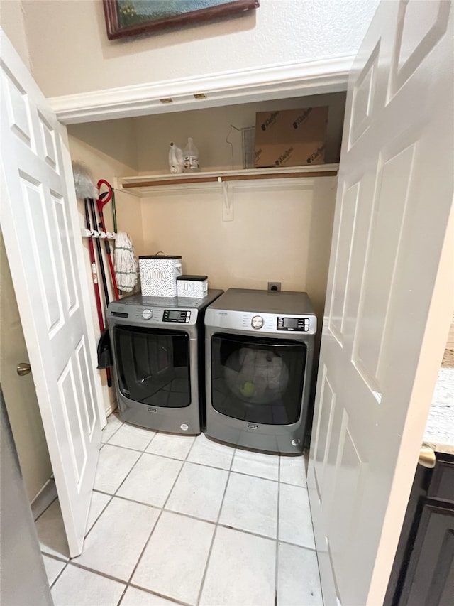 clothes washing area with washer and dryer and light tile flooring