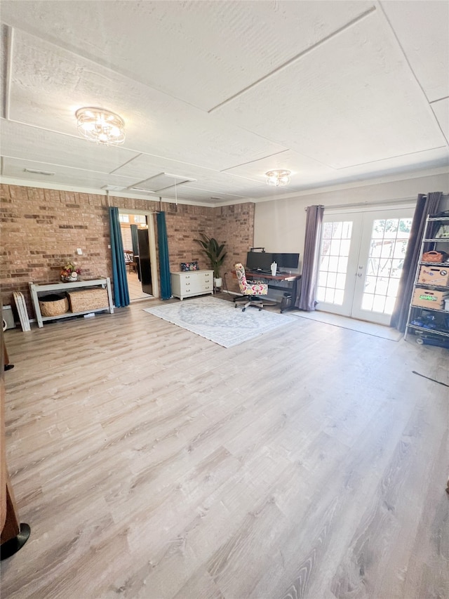 unfurnished living room with french doors, brick wall, and wood-type flooring