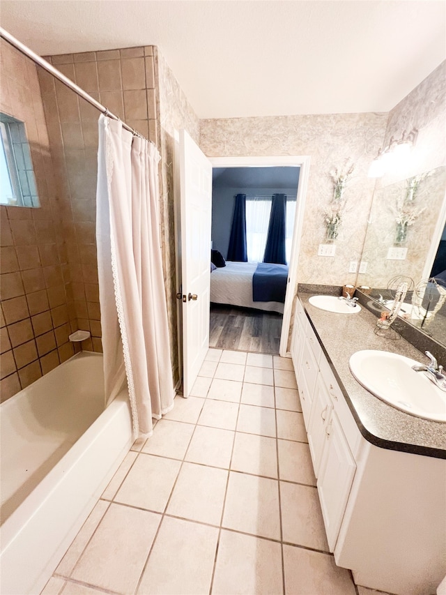 bathroom with tile floors, vanity with extensive cabinet space, shower / tub combo with curtain, and double sink