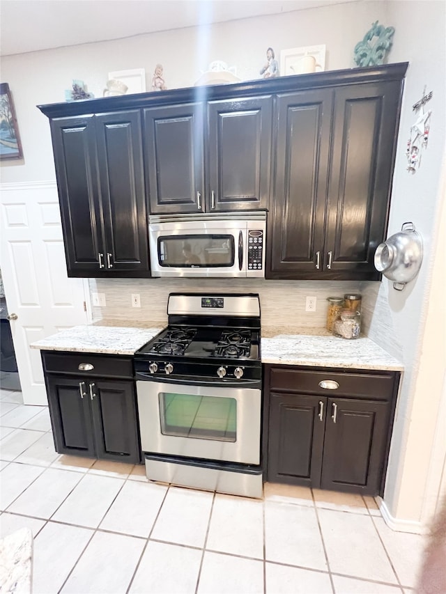 kitchen with light tile flooring, light stone counters, and stainless steel appliances