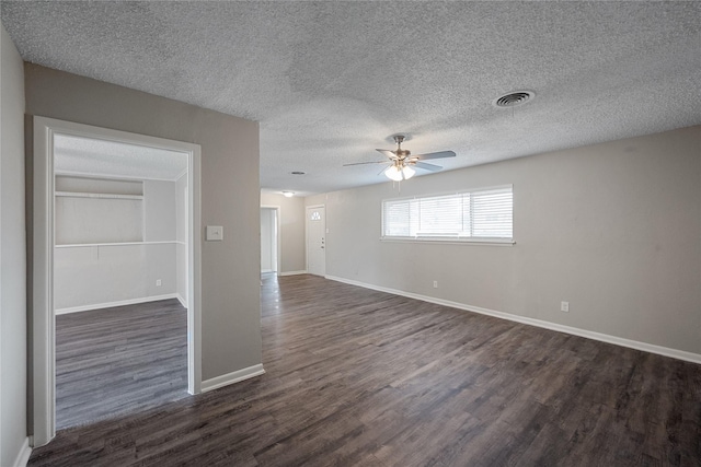 spare room featuring a textured ceiling, ceiling fan, and dark wood-type flooring