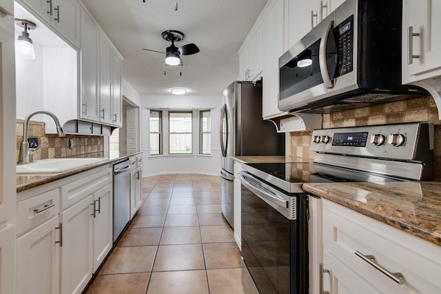 kitchen featuring backsplash, stainless steel appliances, ceiling fan, sink, and white cabinetry