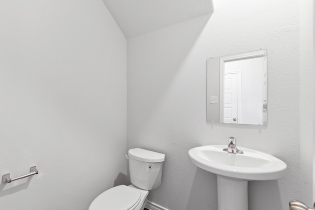 bathroom with lofted ceiling, sink, and toilet