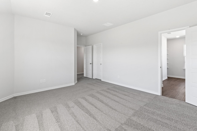 unfurnished bedroom featuring dark colored carpet, recessed lighting, visible vents, a spacious closet, and baseboards