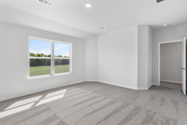 empty room featuring light colored carpet, visible vents, and baseboards