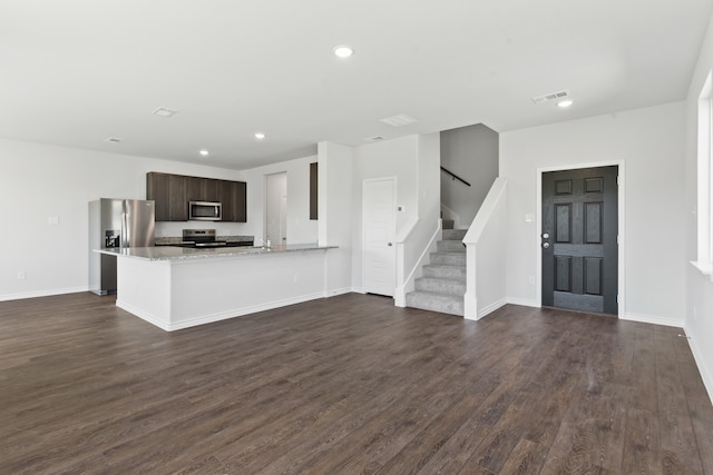 kitchen featuring visible vents, light stone counters, a peninsula, stainless steel appliances, and dark brown cabinets