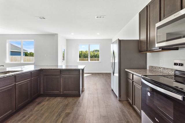 kitchen with stainless steel appliances, visible vents, a sink, and light stone counters