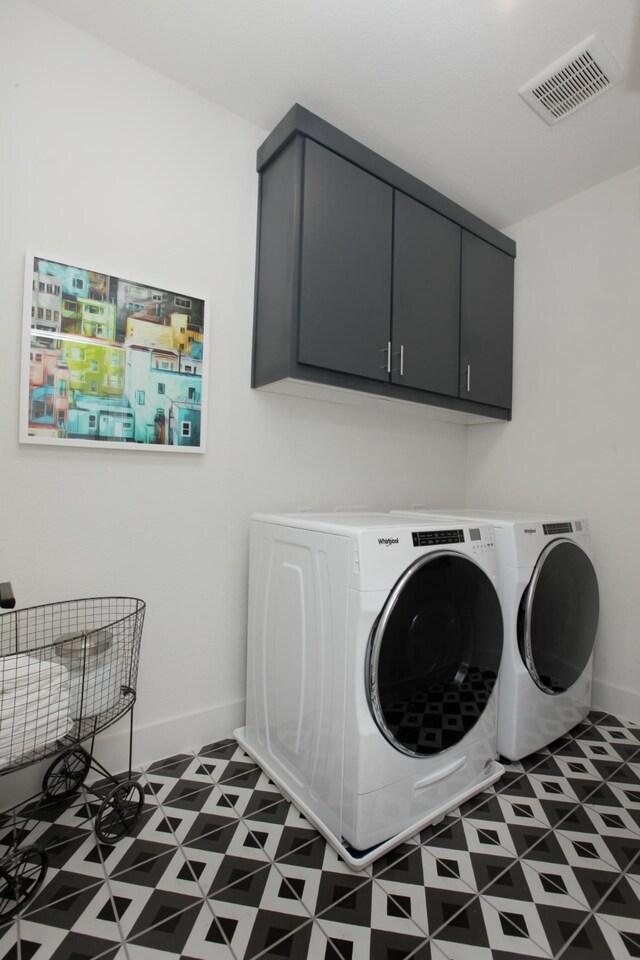 washroom featuring washing machine and clothes dryer, visible vents, cabinet space, baseboards, and tile patterned floors