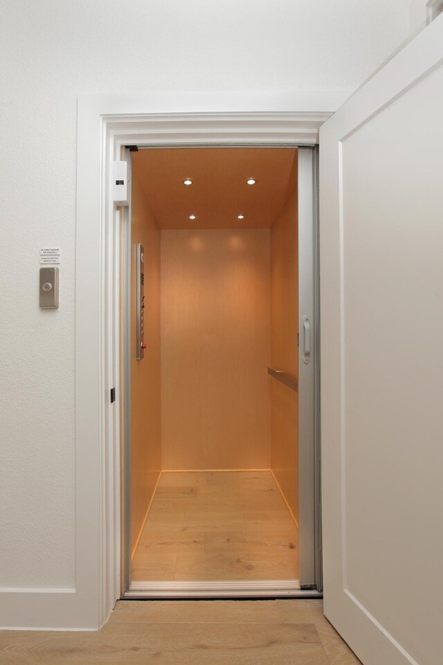 room details featuring recessed lighting, elevator, and wood finished floors