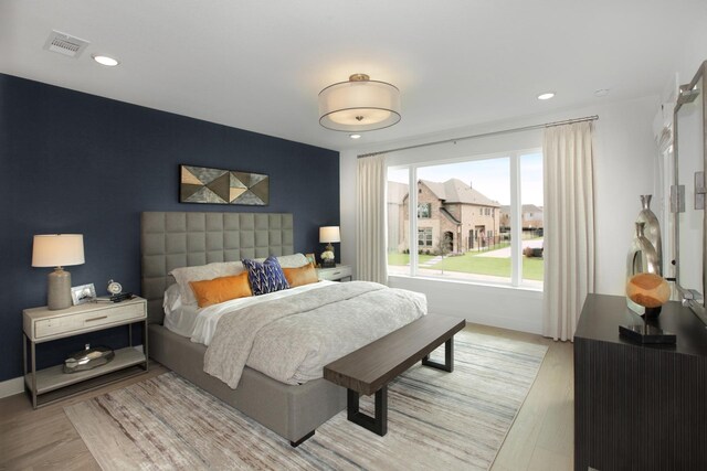 bedroom featuring recessed lighting, an accent wall, visible vents, baseboards, and light wood-type flooring