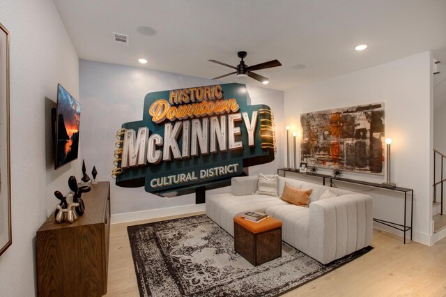 living room with ceiling fan, stairway, baseboards, and wood finished floors