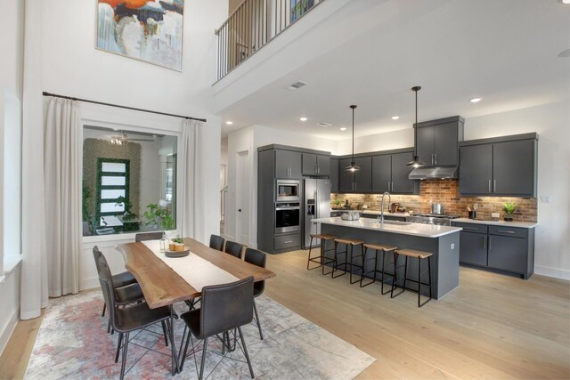 dining area featuring visible vents, baseboards, light wood-style flooring, a high ceiling, and recessed lighting