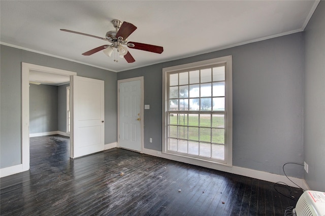 empty room featuring crown molding, baseboards, ceiling fan, and dark wood-type flooring