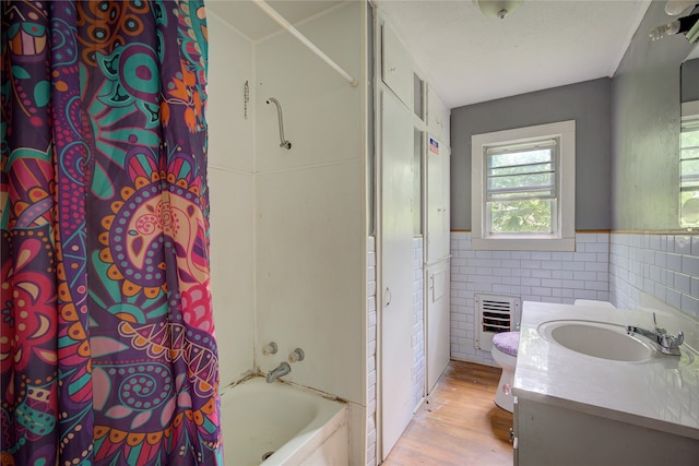 bathroom featuring vanity, wood finished floors, shower / tub combo, wainscoting, and tile walls