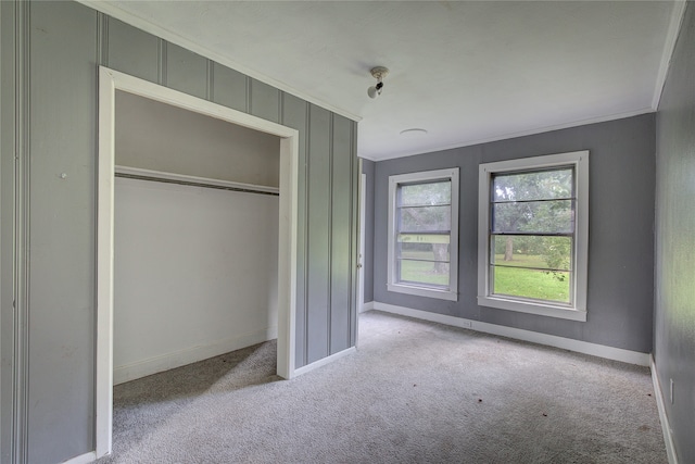 unfurnished bedroom with carpet flooring, a closet, and ornamental molding