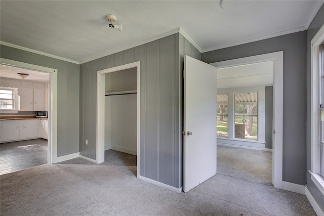 unfurnished bedroom featuring a closet, multiple windows, light colored carpet, and crown molding