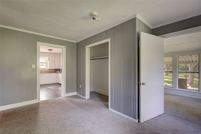 unfurnished bedroom with a closet, baseboards, carpet flooring, and crown molding