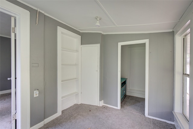 unfurnished bedroom with light carpet, ornamental molding, and wooden walls