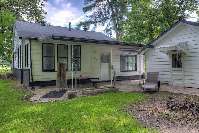 back of property with a patio area, a lawn, and a shingled roof