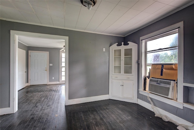 unfurnished dining area featuring a healthy amount of sunlight, ornamental molding, cooling unit, and dark wood-type flooring