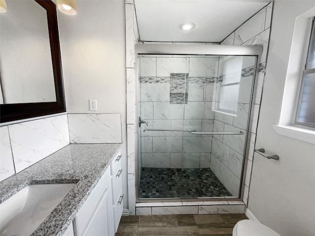 bathroom featuring vanity, a shower with shower door, and toilet