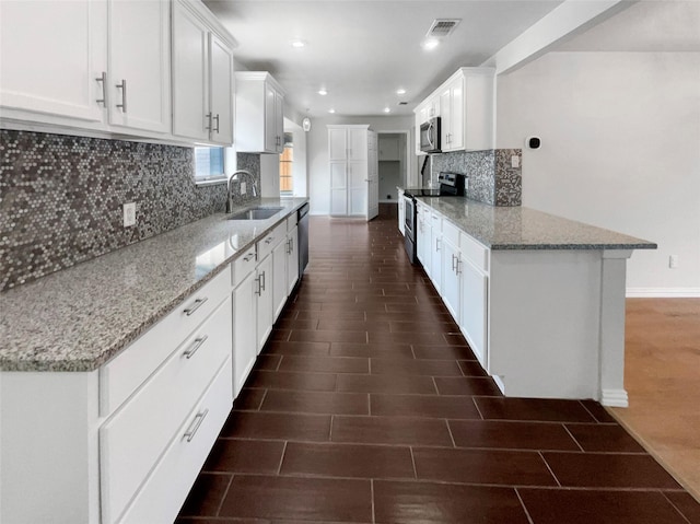 kitchen featuring stainless steel appliances, light stone countertops, sink, and white cabinets