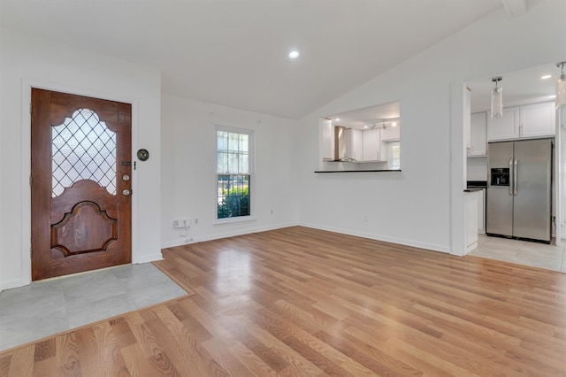 foyer entrance with vaulted ceiling and light hardwood / wood-style flooring