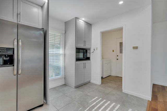 kitchen featuring white cabinets, stainless steel fridge, light wood-type flooring, and washer / clothes dryer