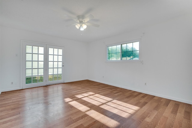 spare room featuring ceiling fan, light hardwood / wood-style flooring, and a wealth of natural light