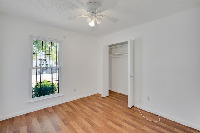 unfurnished bedroom with ceiling fan, a closet, light hardwood / wood-style floors, and a textured ceiling