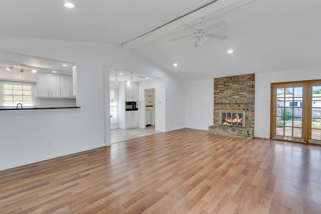 unfurnished living room with a healthy amount of sunlight, vaulted ceiling with beams, and light wood-type flooring