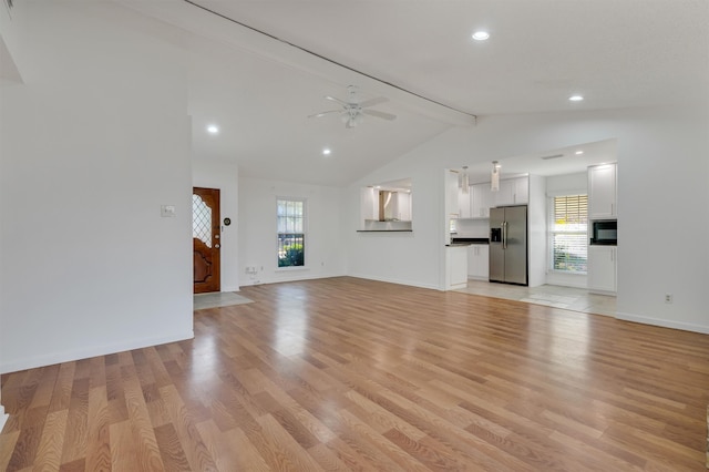 unfurnished living room featuring ceiling fan, lofted ceiling with beams, and light hardwood / wood-style floors