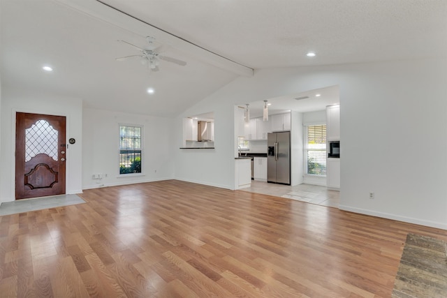 unfurnished living room featuring lofted ceiling with beams, light hardwood / wood-style flooring, and a wealth of natural light