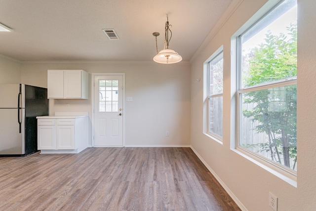 unfurnished dining area featuring crown molding and light hardwood / wood-style flooring