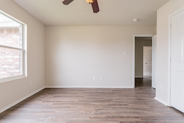 unfurnished room featuring a wealth of natural light, hardwood / wood-style floors, ceiling fan, and a textured ceiling