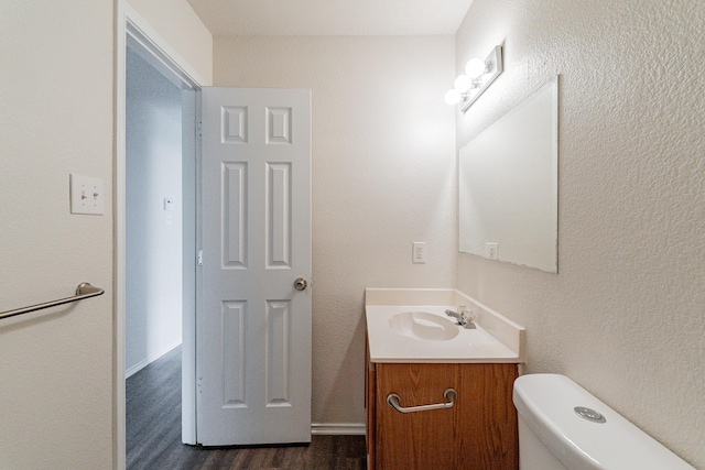 bathroom featuring toilet, vanity, and hardwood / wood-style flooring