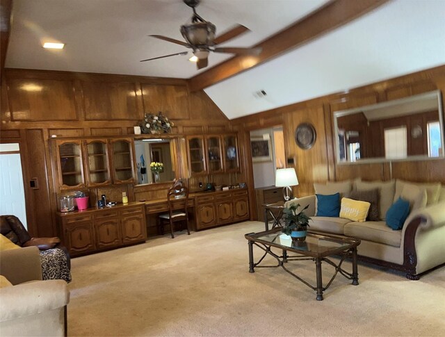 carpeted living room with wood walls, lofted ceiling with beams, and ceiling fan