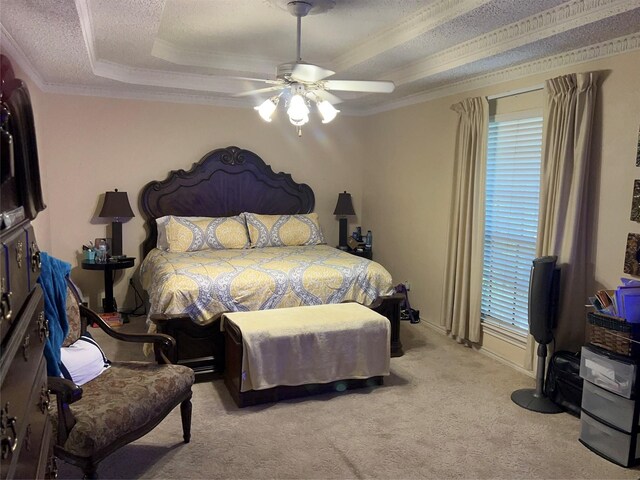 bedroom featuring a tray ceiling, ceiling fan, ornamental molding, a textured ceiling, and light colored carpet