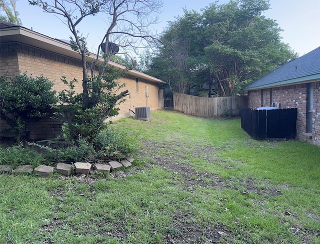 view of yard with central AC and fence