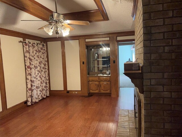 empty room featuring crown molding, a textured ceiling, brick wall, hardwood / wood-style floors, and ceiling fan